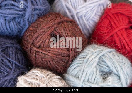 Close-up on woolen knitting balls in different colors. Focus on the threads of the brown knot of wool in the middle Stock Photo
