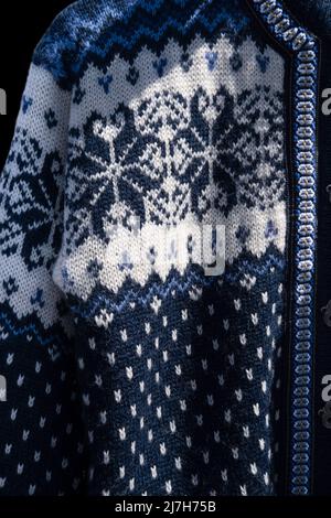 Blue handmade woolen Scandinavian ladies cardigan, Norwegian style sweater with patterns hanging in an open air market stall Stock Photo