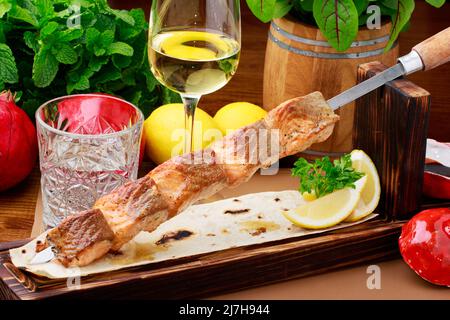 Grilled salmon on stainless steel skewers, served on flat breads with Lemon and Pomegrenate sauce. Stock Photo