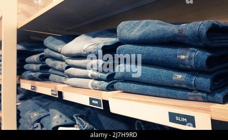 assortment of blue jeans on wooden shelves Stock Photo