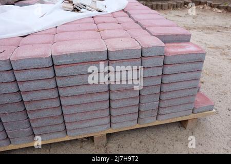 Pink pavement tile folded for the reconstruction of a walkway covered with a plastic film from the rain. Paving blocks as the main paving material for Stock Photo