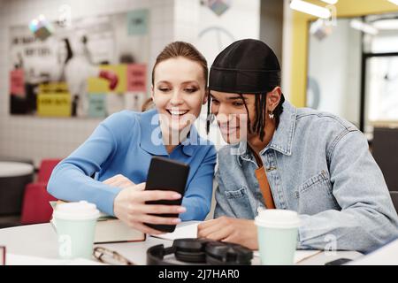 Vibrant shot of two young people taking selfie photo while having fun in college library Stock Photo