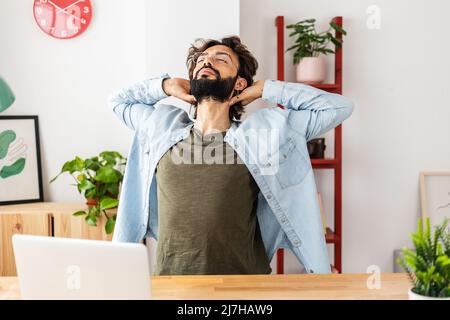 Hipster young man doing a stretching exercise while taking a break from work Stock Photo