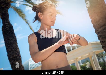 Fitness woman after workout session checks results on smartwatch in fitness app. Healthy lifestyle concept. Female athlete wearing sport tracker wrist Stock Photo