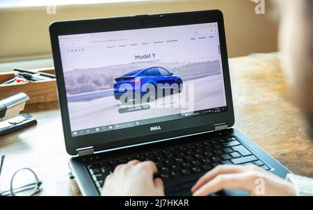 Greece, Athens, January 23 2022. TESLA CAR SELECTION. Ad, online blue Tesla model Y electric auto. Pc on table, hand on keyboard Stock Photo