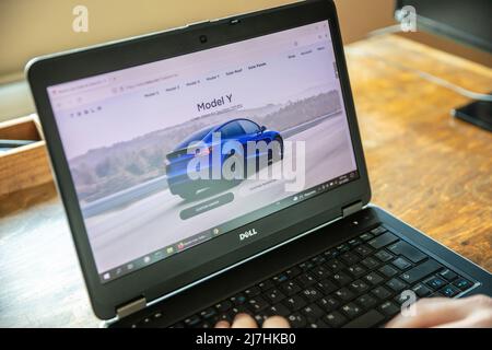 Greece, Athens, January 23 2022. TESLA CAR SELECTION. Ad, online blue Tesla model Y electric auto. Pc on table, hand on keyboard Stock Photo