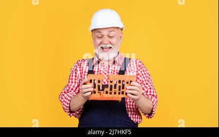 smiling senior man worker in helmet on yellow background Stock Photo
