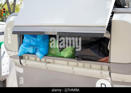 Overloaded street garbage container for recycling. Waste management company missed pickup. Trash piled up Stock Photo