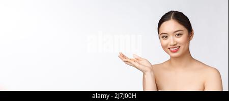 Young attractive asian woman who takes a capsule or pill. Isolated over white background. Stock Photo