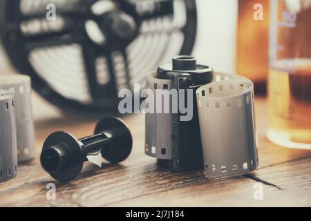 Photo film rolls and cassette, photographic equipment - developing tank with its film reels and chemical reagents on background. Stock Photo