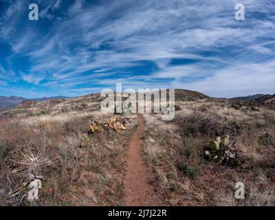 Hiking path going up a desert mountain with a cloudy sky. Stock Photo