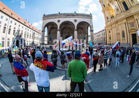 Munich, Bavaria, Germany. 9th May, 2022. Coinciding with the May 9th victory celebrations, a max of just under 100 pro-Russia actors assembled in Munich, Germany to protest against supposed 'discrimination'' against Russian-speaking people. Such claims of non-existent discrimination are included in warnings as potential Kremlin-directed hybrid warfare propaganda campaigns. The imagery of the celebration taking place at the Munich Feldherrnhalle was not lost on outraged passersby who saw it as 'historical revisionism'' and 'incitement''. Approximately 125 from the Ukrainian and Belaru Stock Photo