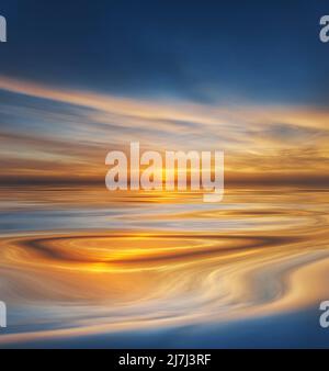 A golden sunrise or sunset casts a warm glow over calm water, reflecting shimmering light Stock Photo