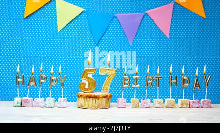 Number 57 blue celebration candle and gold confetti on dark wooden ...