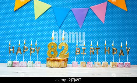 Happy birthday from candle letters on a blue background with white polka dot copy space. Happy birthday cupcake with burning golden candle Stock Photo