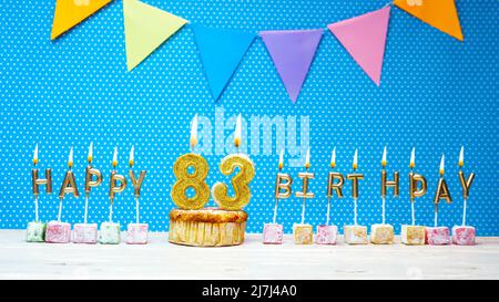 Happy birthday from candle letters on a blue background with white polka dot copy space. Happy birthday cupcake with burning golden candle Stock Photo