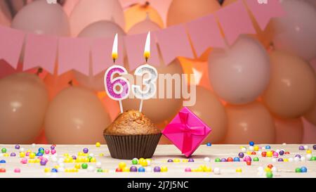 Balloon decorations and a happy birthday candle with a number in a cake. Happy birthday greetings in pink colors for a girl, copy space. Muffin Stock Photo