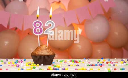 Balloon decorations and a happy birthday candle with a number in a cake. Happy birthday greetings in pink colors for a girl, copy space. Muffin Stock Photo