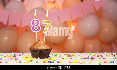 Balloon decorations and a happy birthday candle with a number in a cake. Happy birthday greetings in pink colors for a girl, copy space. Muffin Stock Photo