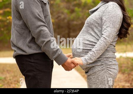 Expecting Couple Holding Hands At The Park Stock Photo