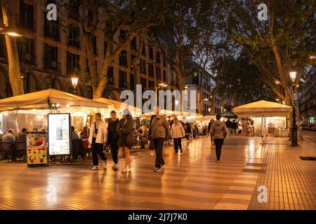 Barcelona, Spain - April 25, 2022:  Street scene along historic La Rambla in Barcelona at night with people. Stock Photo