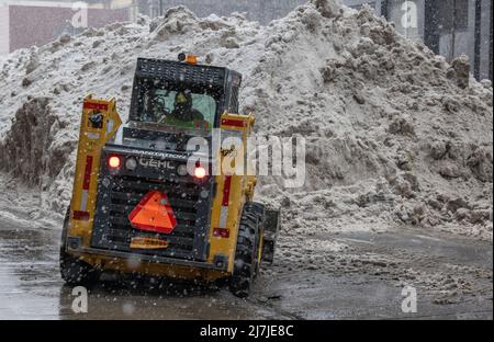 NEW YORK, N.Y. – February 7, 2021: A driver operates a New York City Sanitation Department vehicle near a snow deposit in Lower Manhattan. Stock Photo