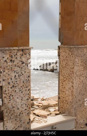 Fisherman house destroyed by a storm on the shore of the Mediterranean Sea in Andalusia, Spain. View through a fence. Stock Photo