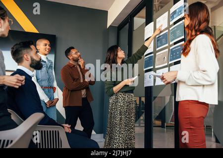 Manager analyzing some business reports with her team. Group of multicultural businesspeople having a meeting in a modern boardroom. Young entrepreneu Stock Photo
