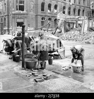 German women washing clothes at a cold water hydrant in a Berlin street, World War II. Stock Photo