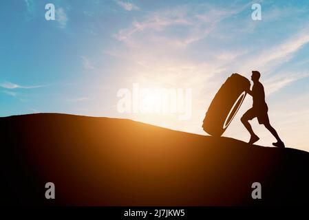 Driving and goals Man doing sports car tire mountain top sunset Stock Photo