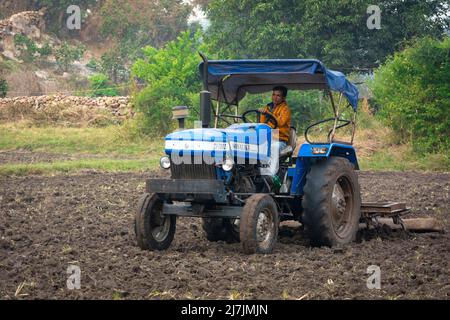 TIKAMGARH, MADHYA PRADESH, INDIA - MAY 02, 2022: Indian farmer working with tractor in agriculture field. Stock Photo