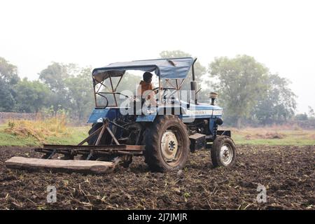 TIKAMGARH, MADHYA PRADESH, INDIA - MAY 02, 2022: Indian farmer working with tractor in agriculture field. Stock Photo