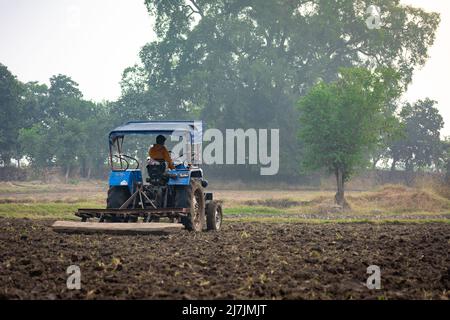TIKAMGARH, MADHYA PRADESH, INDIA - MAY 02, 2022: Indian farmer working with tractor in agriculture field. Stock Photo