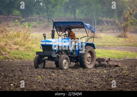 TIKAMGARH, MADHYA PRADESH, INDIA - MAY 02, 2022: Indian farmer working with tractor in agriculture field. Stock Photo