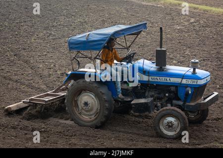 TIKAMGARH, MADHYA PRADESH, INDIA - MAY 02, 2022: Indian farmer working with tractor in agriculture field. Stock Photo