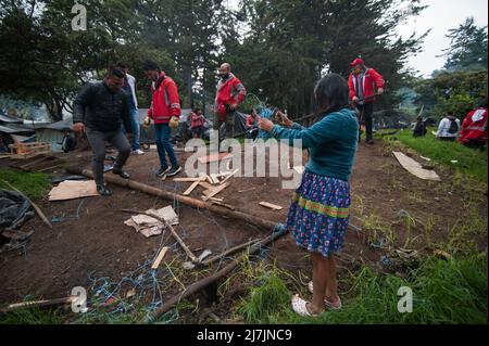 Bogota, Colombia May 9, 2022. An Embera Indigenous mother helps members of Bogota's social office to dismantle a shed as Embera indigenous communities start leaving the makeshift camp mounted 8 months ago where more than 1000 indigenous people displaced by conflict lived and reached agreements with the government to be transferred to a nearby location before returning to their territories, in Bogota, Colombia May 9, 2022. Photo by: Chepa Beltran/Long Visual Press Stock Photo