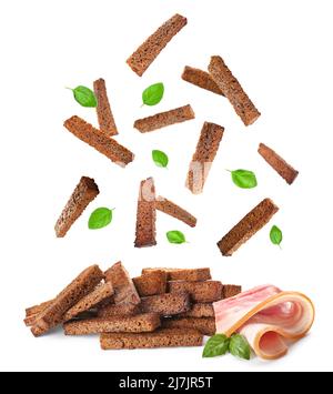 Falling rye croutons with basil leaves and bacon on white background Stock Photo