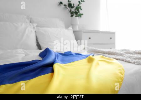 Flag of Ukraine on modern bed in light room, closeup Stock Photo