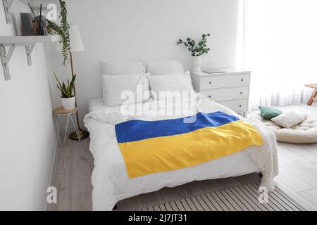 Interior of light bedroom with Ukrainian flag and houseplants Stock Photo