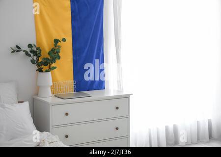 Flag of Ukraine hanging on light wall in modern bedroom Stock Photo