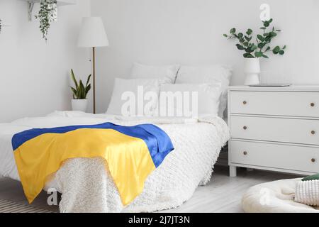 Interior of light bedroom with Ukrainian flag and houseplants Stock Photo