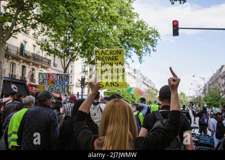 Paris, France. 07th May, 2022. (EDITORS NOTE: Image contains profanity)A yellow vest holds a placard during the demonstration and gestures against French President Emmanuel Macron during the protest. Hundreds of 'Yellow Vests' ('Gilets Jaunes' in french) rallied in Paris to protest against the French government of Emmanuel Macron. They protest against basic necessities, social tax, and climate justice inflation. They also demand the Citizen Initiated Referendum (RIC in french). Credit: SOPA Images Limited/Alamy Live News Stock Photo