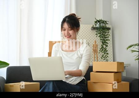 Attractive and charming asian young female business startup online shopping store answering the customer question on the website via laptop computer. Stock Photo