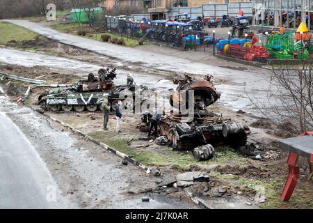 2022-04-09 Kyiv region, Ukraine. People looking at dead russian tanks on the E40 road. War in Ukraine Stock Photo