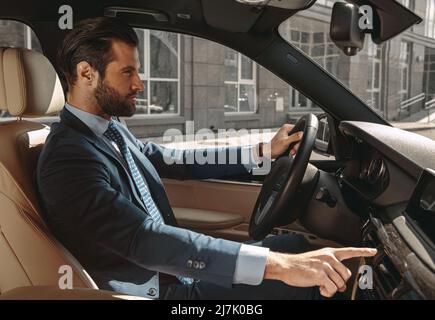 Seriously male entrepreneur in formal clothes traveling by automobile Stock Photo