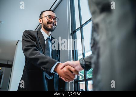portrait of asian businessmen shaking hands and smiling Stock Photo