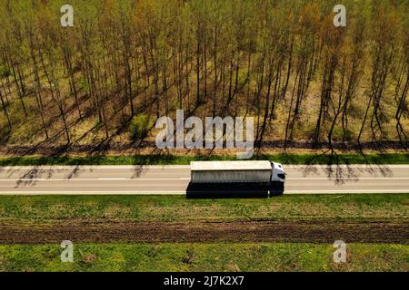 High angle view aerial shot of semi-truck on highway with wooded landscape in background, transportation industry concept Stock Photo