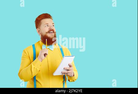 Funny joyful eccentric chubby male nerd with notebook in hands thinking over ideas. Stock Photo