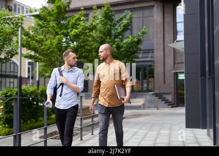 On the go meeting in downtown near office. Real estate managers or financial business team talking outdoor modern building background. Construction, architecture specialist concept. High quality image Stock Photo