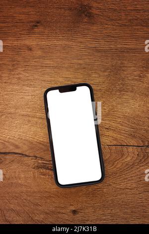 Smartphone with blank white mockup touchscreen on teak wooden table, top view Stock Photo
